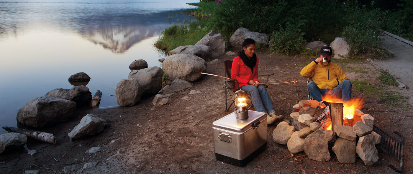 couple sitting beside a campfire next to a lake with a reflection of Mt. Hood