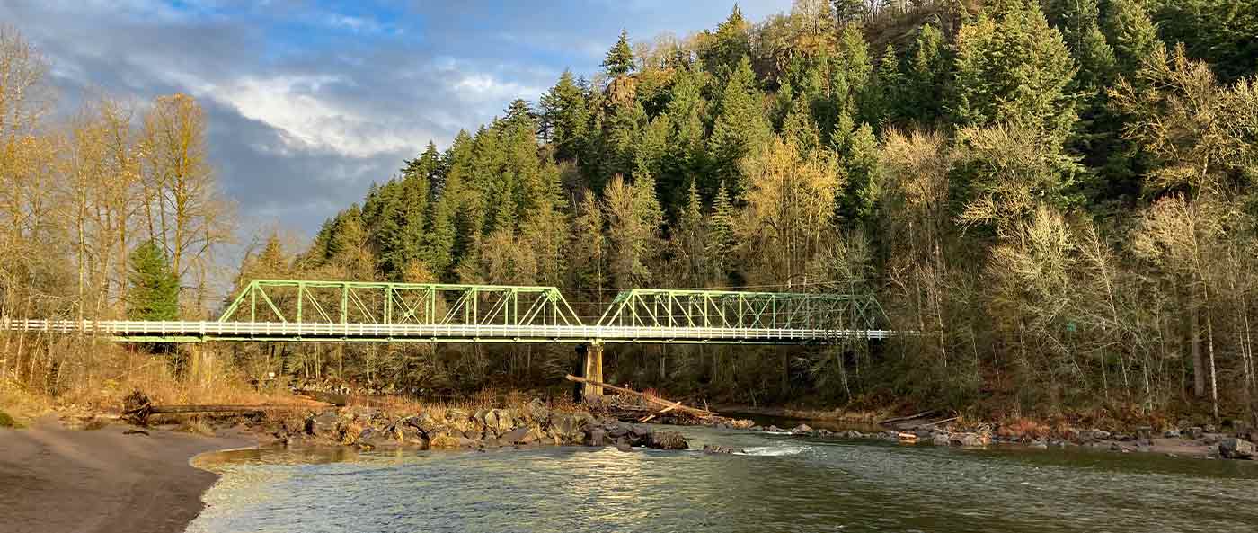green bridge over river along mountain